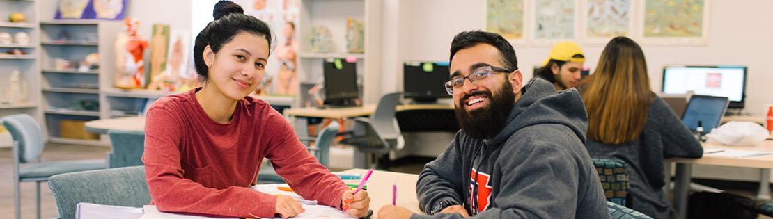 A student tutor assists another student in a Pima library common area